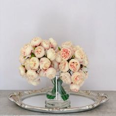 a vase filled with white flowers sitting on top of a silver tray