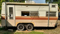 an old trailer is parked in the grass