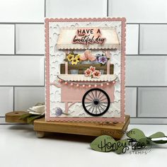 a handmade birthday card with an ice cream cart and flowers on the front, sitting on a wooden stand