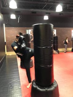 a man standing next to a punching bag on top of a red floor in a gym