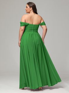 a woman in a long green dress with her back turned to the camera, looking down