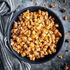 roasted chickpeas in a black bowl on top of a gray table with a striped towel