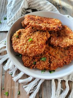 some fried food in a white bowl on a wooden table with a cloth and napkin