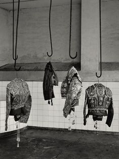 several coats hanging from hooks in a tiled room