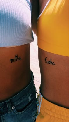 two women with matching tattoos on their stomachs, both showing the same word as each other