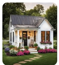 a small white house with flowers in the front yard