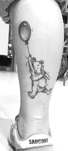 a black and white photo of a person's foot with a bear holding a balloon