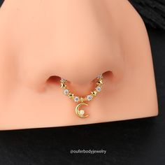 an earring with a crescent and stars on the end is sitting on a mannequin's head