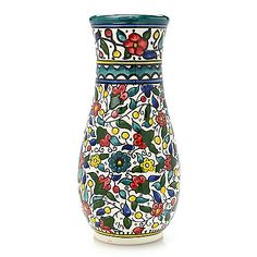 a colorful vase with flowers and leaves painted on the outside, sitting on a white surface