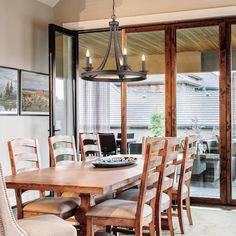 a dining room table with chairs and a chandelier hanging from it's ceiling