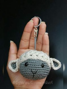 a crocheted sheep keychain is held in someone's hand