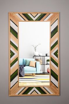 a living room with a blue couch and green striped mirror on the wall above it