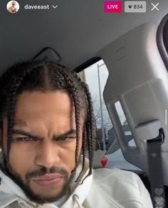 a man with dreadlocks in the back seat of a car