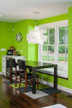 a dining room with green walls and wooden floors