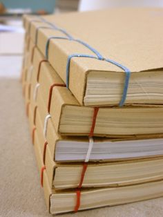 three books stacked on top of each other with red and blue string wrapped around them