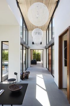 a long hallway with lots of windows and lights hanging from it's ceiling, leading to the dining room