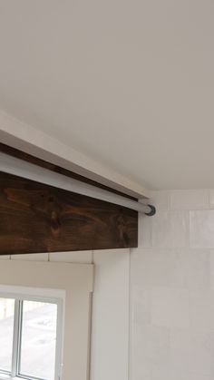 a bathroom with white tile and wood trim on the ceiling, along with a window