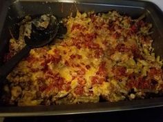 a casserole dish with meat and cheese in it on a stove top next to a spatula