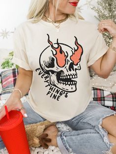 Show off your style with our Everything Is Fine Shirt! This Comfort Colors® Tee features a trendy skull graphic, blending boho and vintage graphic tee. Perfect for fans of sarcastic memes and skeleton designs, this Boho Hippie Shirt is a must-have for a bold look. Hi! Welcome To TeeTaniumCo! THE FIT True to size (Relaxed fit) Comfortable unisex fit 100% cotton Professional high-quality print Don't forget to consult our size cards for that perfect fit! Your Shopping Experience is Paramount! We deeply value your time and trust, and we're committed to assisting you at every step. Have questions? Don't hesitate to reach out! Discover Your Ideal Fit Swift Processing, Punctual Delivery Our team ensures prompt processing and production within 1-2 business days. Delivery times may vary based on yo Band Merch Crew Neck Top With Skull Print, Crew Neck Skull Print Band Merch Top, Crew Neck Skull Print Top Band Merch, Edgy Cotton Tops With Skull Print, Trendy Cotton Skull Print Tops, Edgy Skull Print Crew Neck Top, Skull Screen Print Relaxed Fit Tops, Edgy Tops With Halloween Front Print, Edgy Tops With Front Print For Halloween