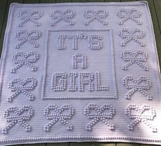 a white crocheted blanket with letters and numbers on the bottom is laying on a wooden floor