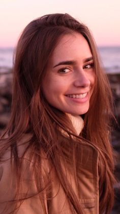 a woman standing next to the ocean smiling