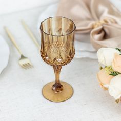 a table set for two with flowers and gold utensils on the place setting