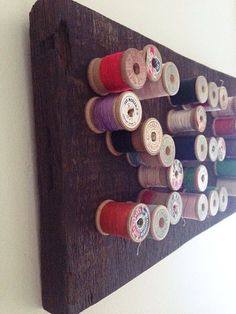 several spools of thread are hanging on a wall