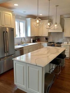 a large kitchen with an island in the middle and lots of lights hanging from the ceiling