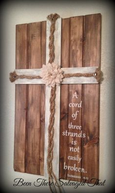 a cross made out of wooden planks with a rope tied to the bottom and words on it