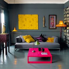 a living room filled with furniture and colorful paintings on the wall above it's coffee table