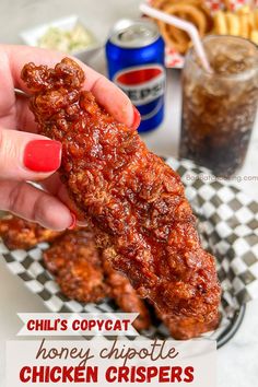 a person is holding up a chicken crisper in front of some drinks and snacks