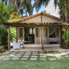 a small house with a table and chairs in front of it, surrounded by palm trees