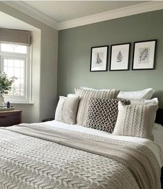 a bedroom with green walls and white bedding, two framed pictures on the wall