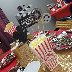 popcorn buckets and movie clapers on a table at a birthday party with gold sequins