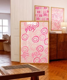 a room with wooden floors and two paintings on the wall next to a coffee table