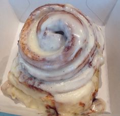 a cinnamon roll sitting in a box with icing on it's top and bottom