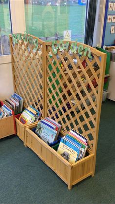 a wooden bench filled with books in front of a window next to a green carpet