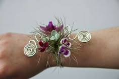 a woman's arm with flowers and spirals on the wrist, in front of a gray background