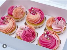 cupcakes with pink frosting and pearls in a white box on a table