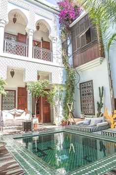 an outdoor swimming pool in the middle of a courtyard with potted plants on either side