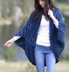 a woman wearing a blue crocheted cardigan and holding her hands out to the side