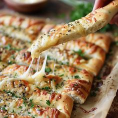 a person is dipping cheese on top of a cheesy pizza slice with parsley