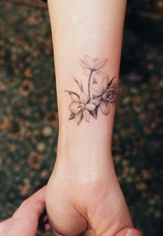 a woman's arm with a small flower tattoo on the left side of her wrist