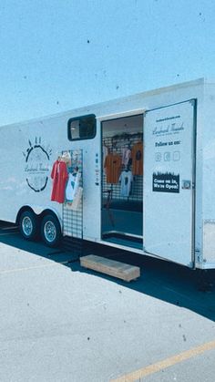 a white trailer parked on top of a parking lot next to a building with an open door