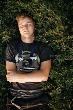 a man laying in the grass with a camera on his chest and eyes closed, taking a selfie