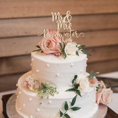 a white wedding cake with pink flowers and mr and mrs topper on the side