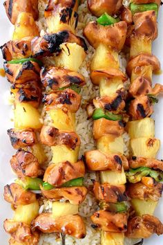 chicken and pineapple skewers with rice on a white platter, ready to be served