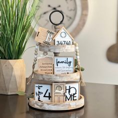 a wooden clock tower sitting on top of a table next to a potted plant