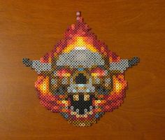 a piece of art made out of perler beads on a wooden surface with an image of a skull in the middle