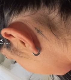 a woman with a small cross tattoo on her ear